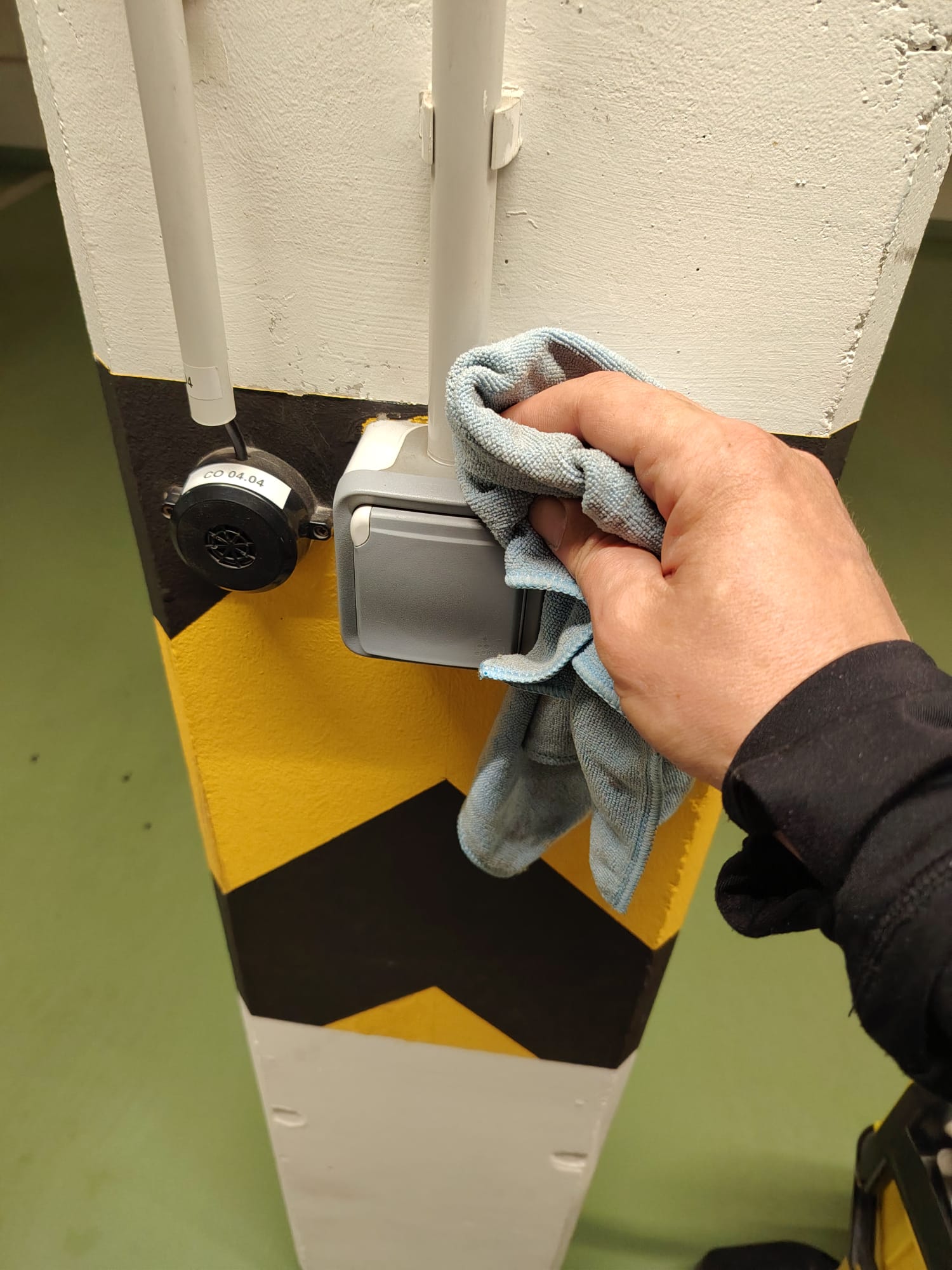 Ruční čištění elektroinstalace na sloupu v podzemní garáži